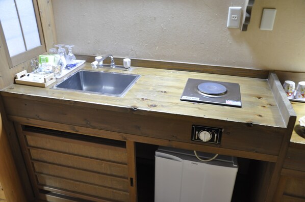 Una pequeña cocina americana con encimera de madera, un lavabo, lavavajillas y un refrigerador compacto.