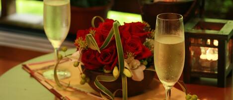A table with two glasses of champagne, a bottle of champagne, red roses, and a lantern.