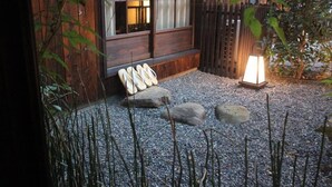 Une cabane en bois avec un banc en pierre et une lanterne dans le jardin.
