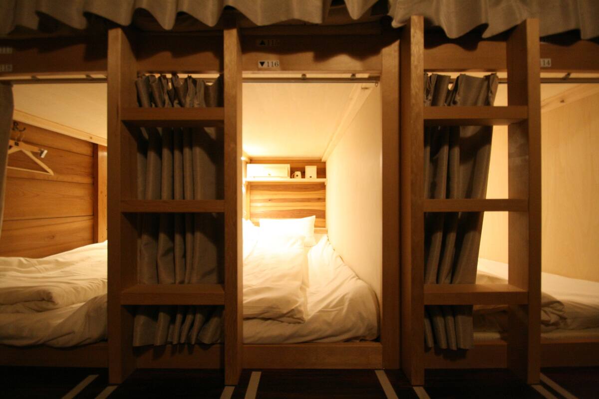 Une chambre avec deux lits superposés en bois, chacun étant doté d’une étagère au-dessus pour ranger les affaires.