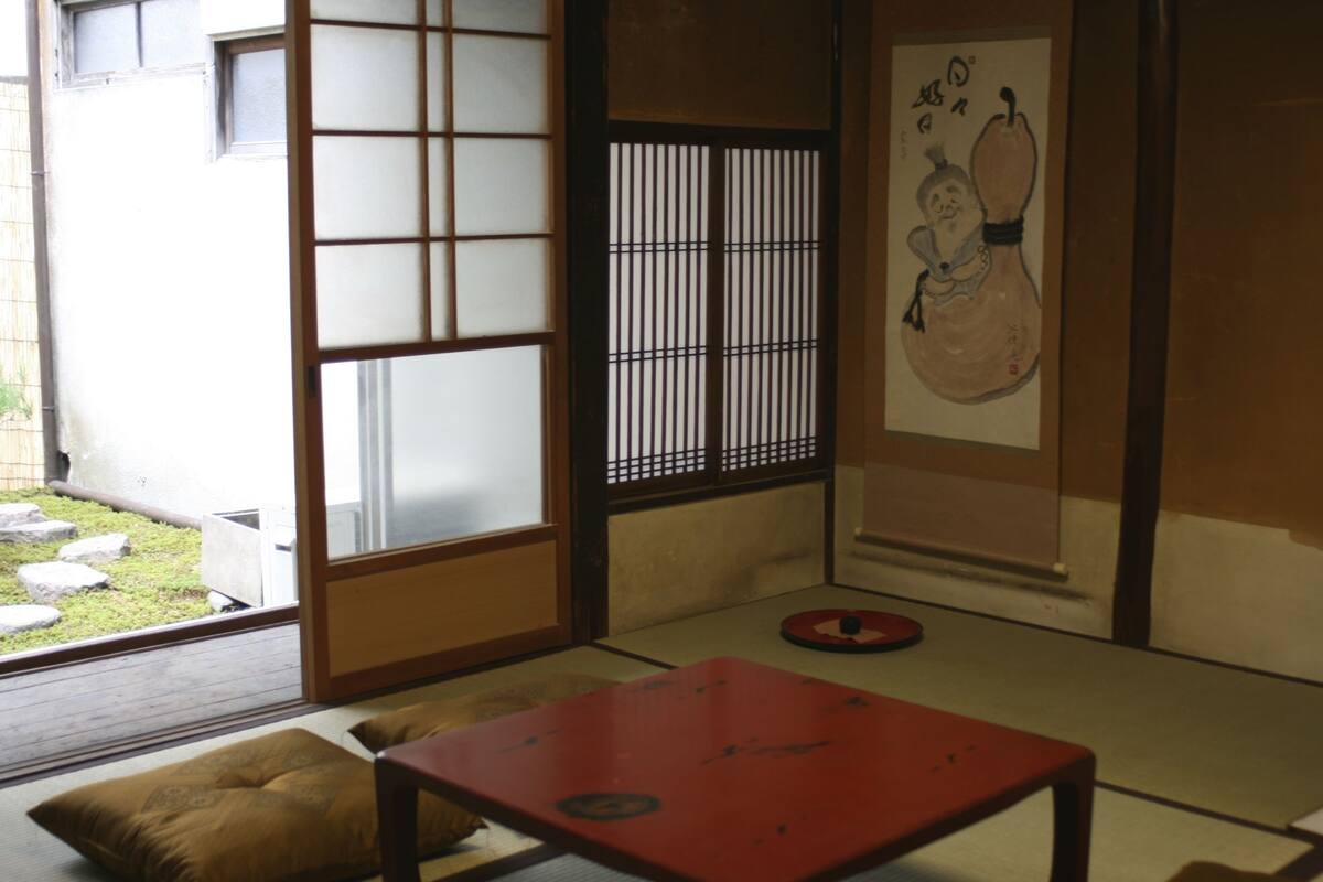 Une pièce de style japonais traditionnel, avec un sol recouvert de tatamis, une porte coulissante de type shoji et une table rouge.