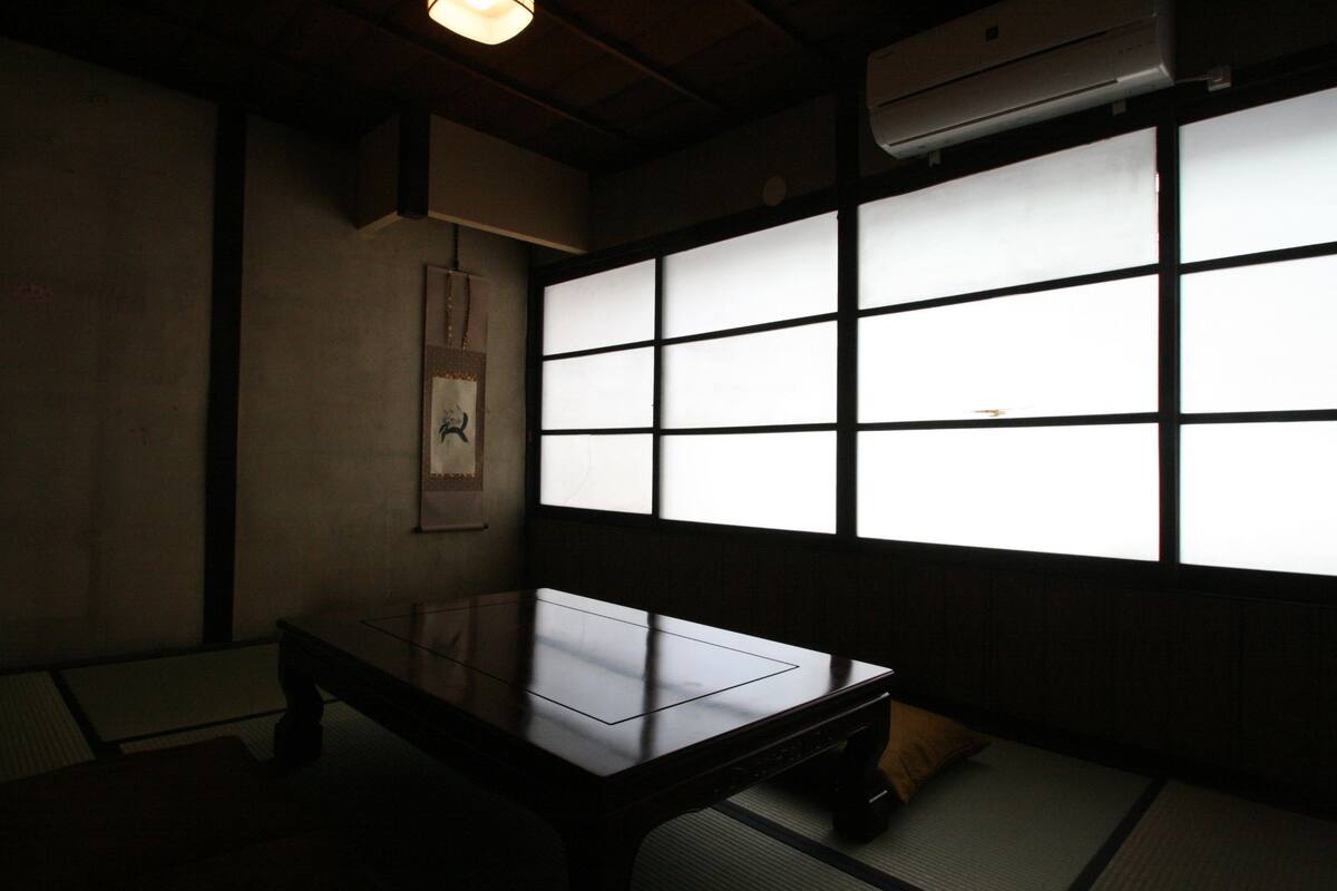 Une pièce de style japonais traditionnel, avec un sol recouvert de tatamis, une table basse et des paravents coulissants (shoji).