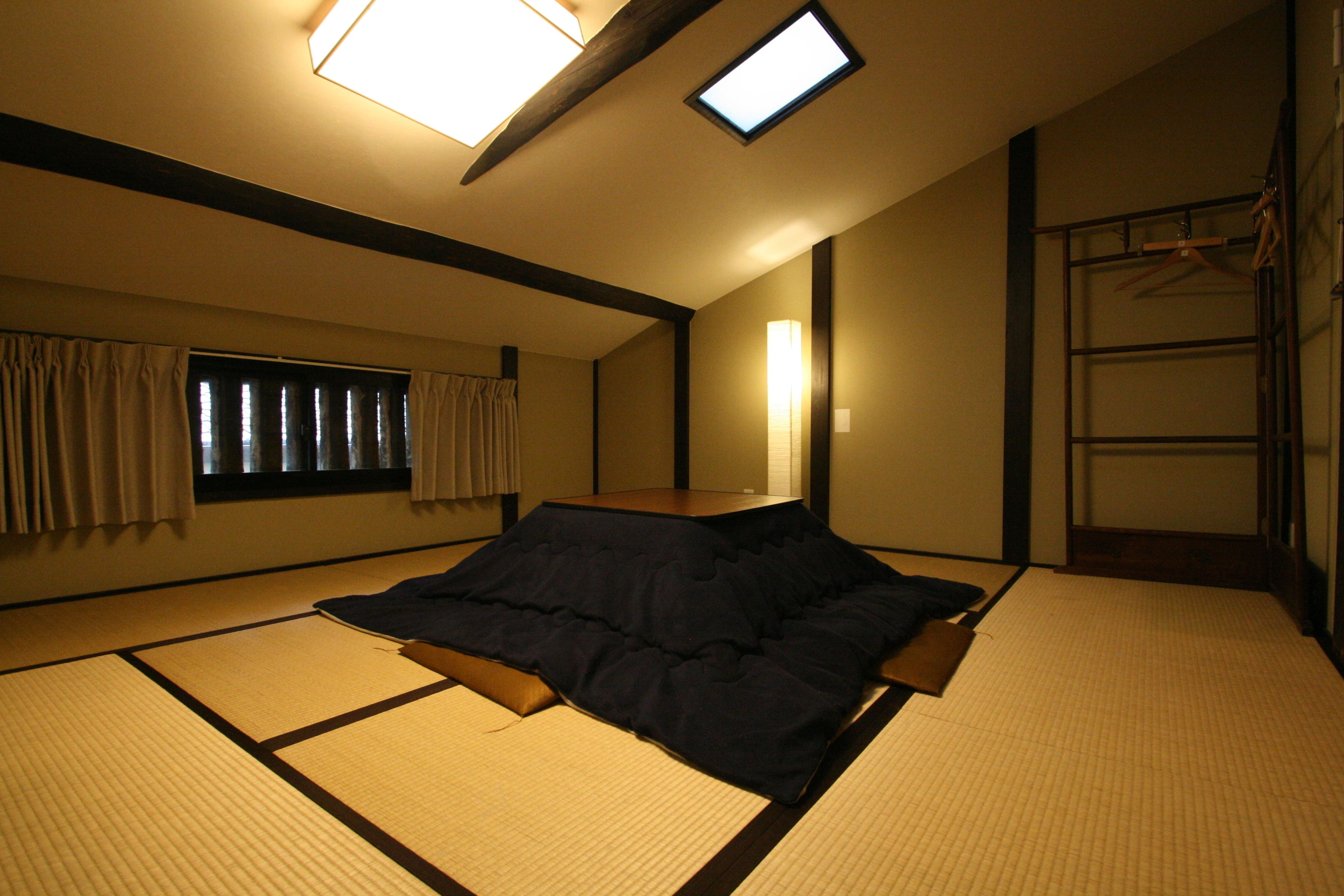 A tatami mat room with a futon bed, a window with curtains, a wall-mounted shelf, and a ladder.