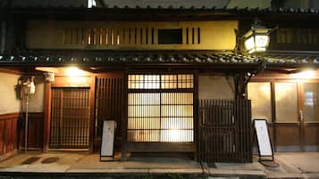 Traditional Japanese building with a tiled roof and wooden elements, featuring a wooden gate and lantern.