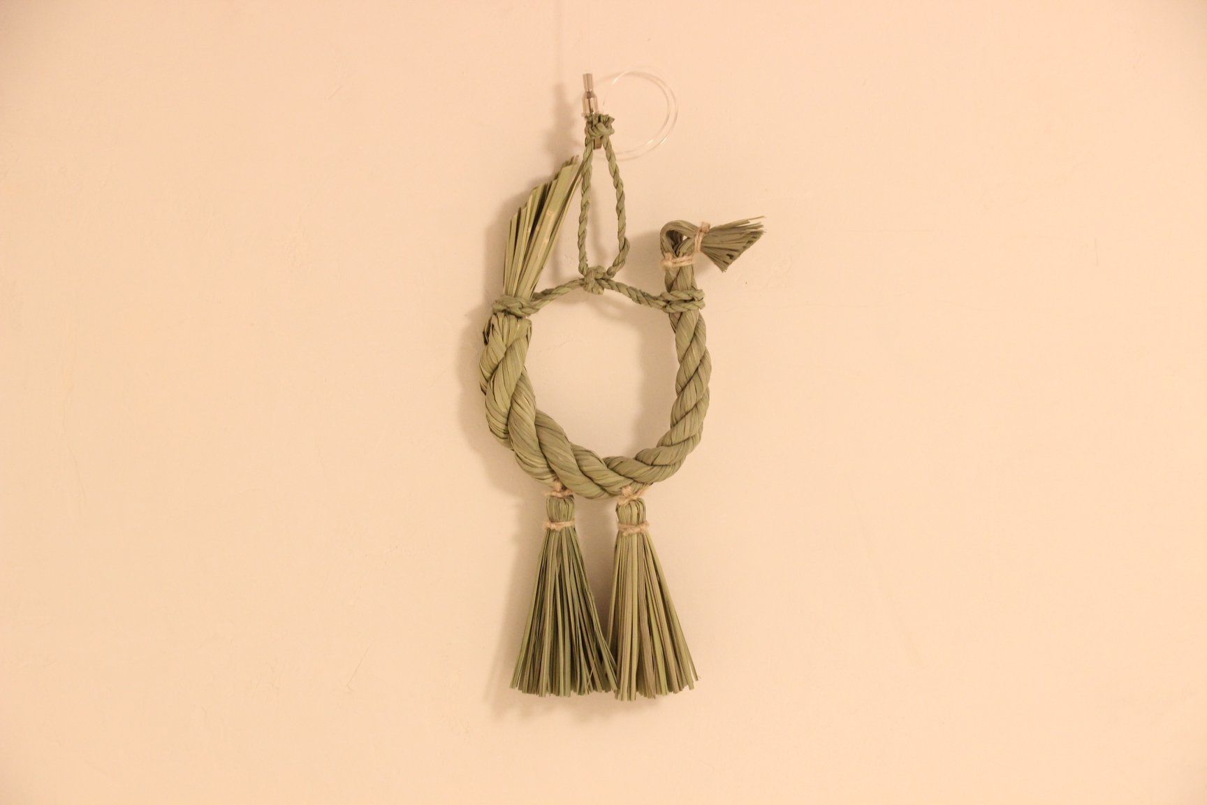 A wall-mounted decorative item with a twisted rope design and tassels.