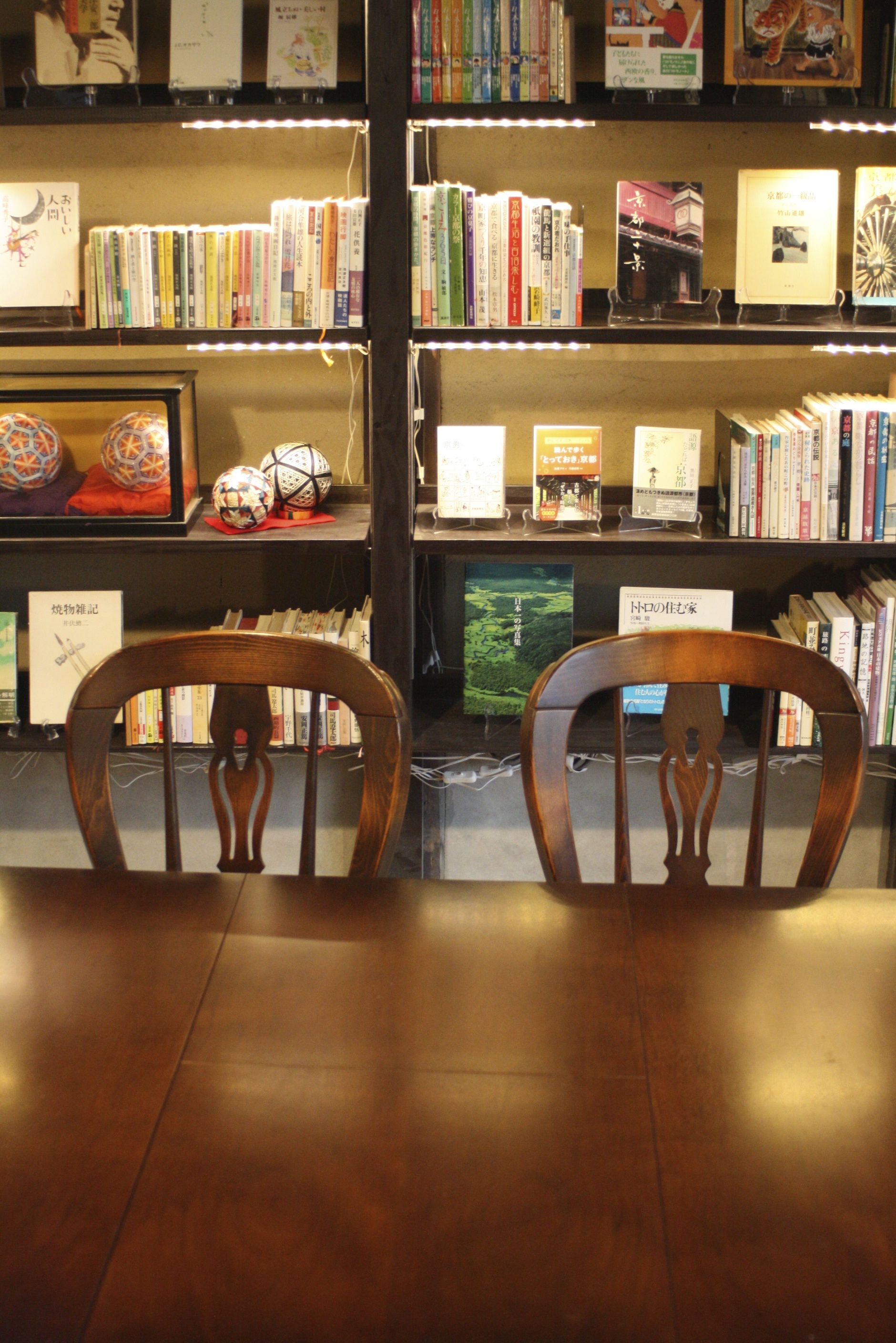 A library with bookshelves and two wooden chairs in the foreground.