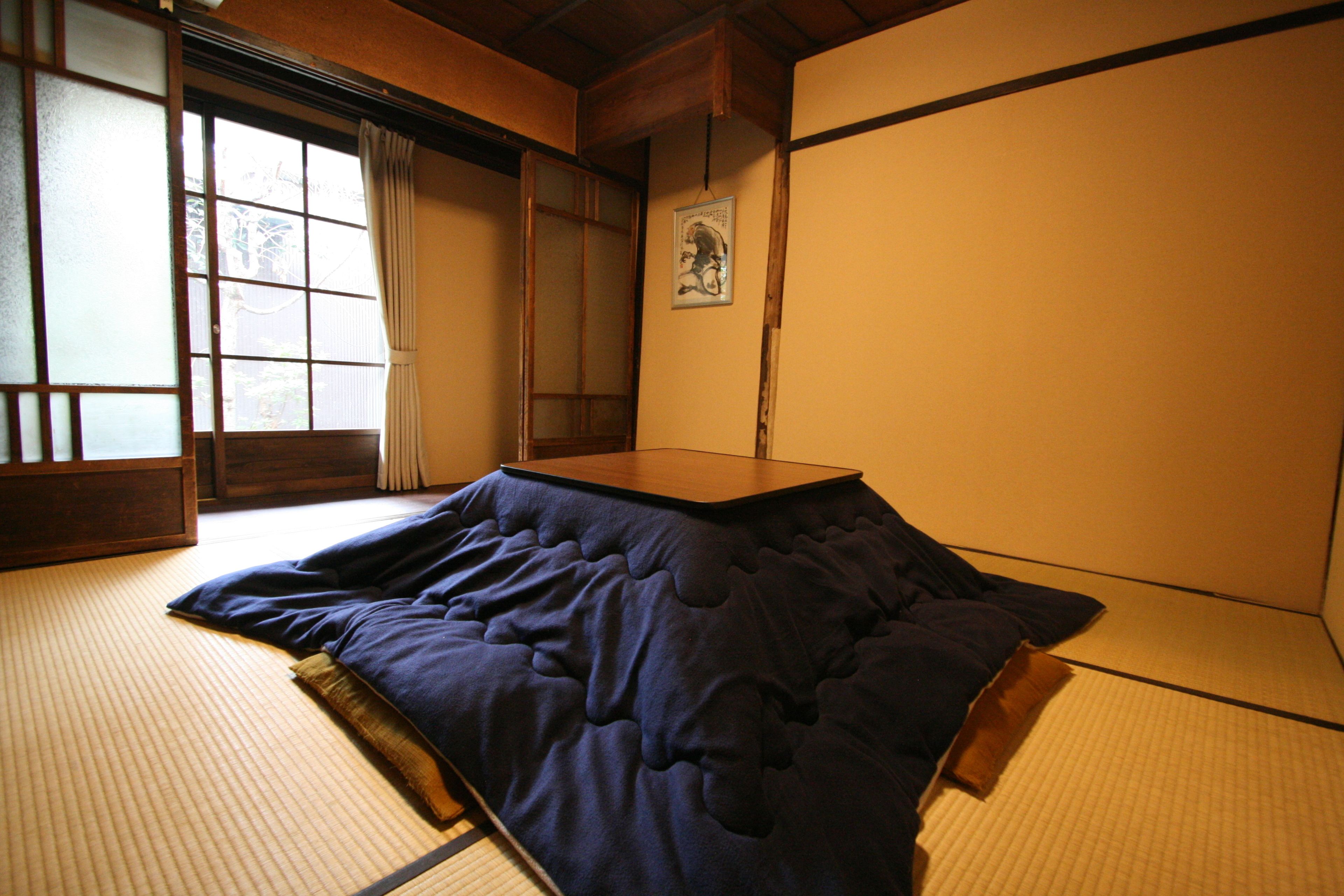 A tatami mat room with a low platform bed, sliding shoji doors, and a framed picture on the wall.