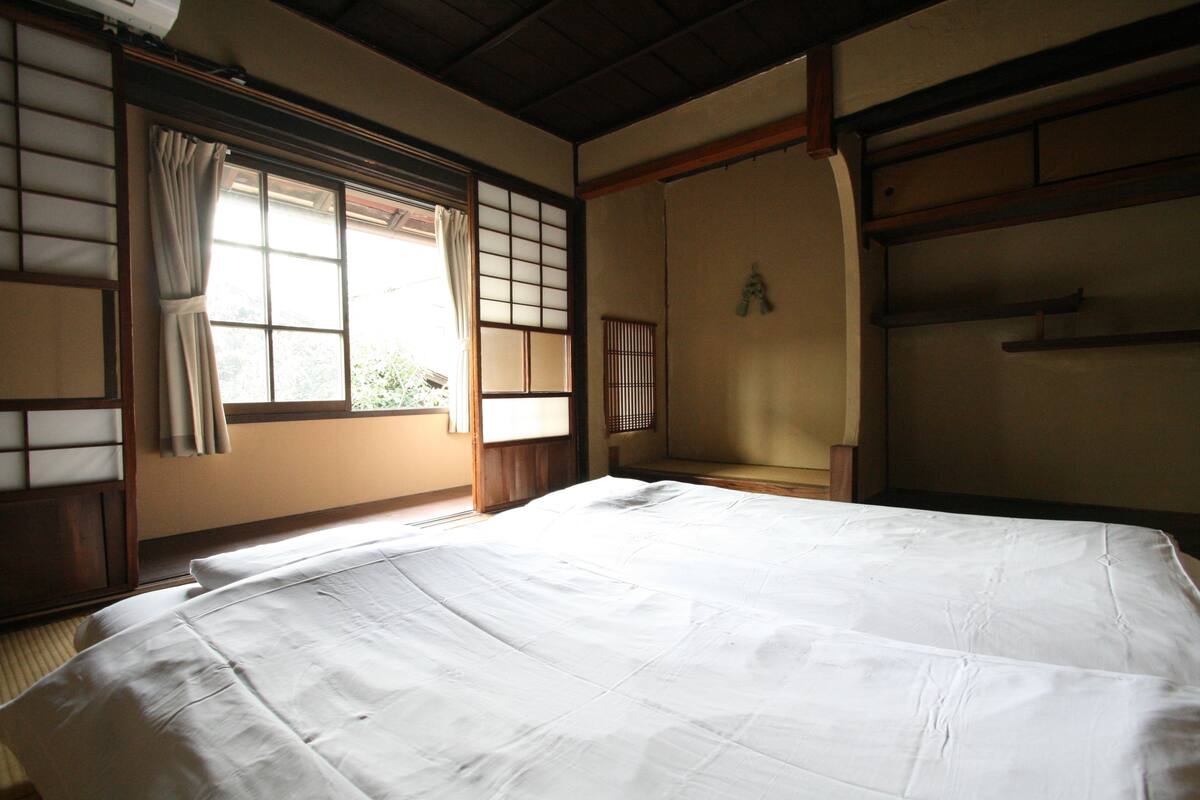 Une pièce de style japonais traditionnel, avec un sol recouvert de tatamis, un futon servant de lit, des portes coulissantes et un paravent en papier de riz (shoji).