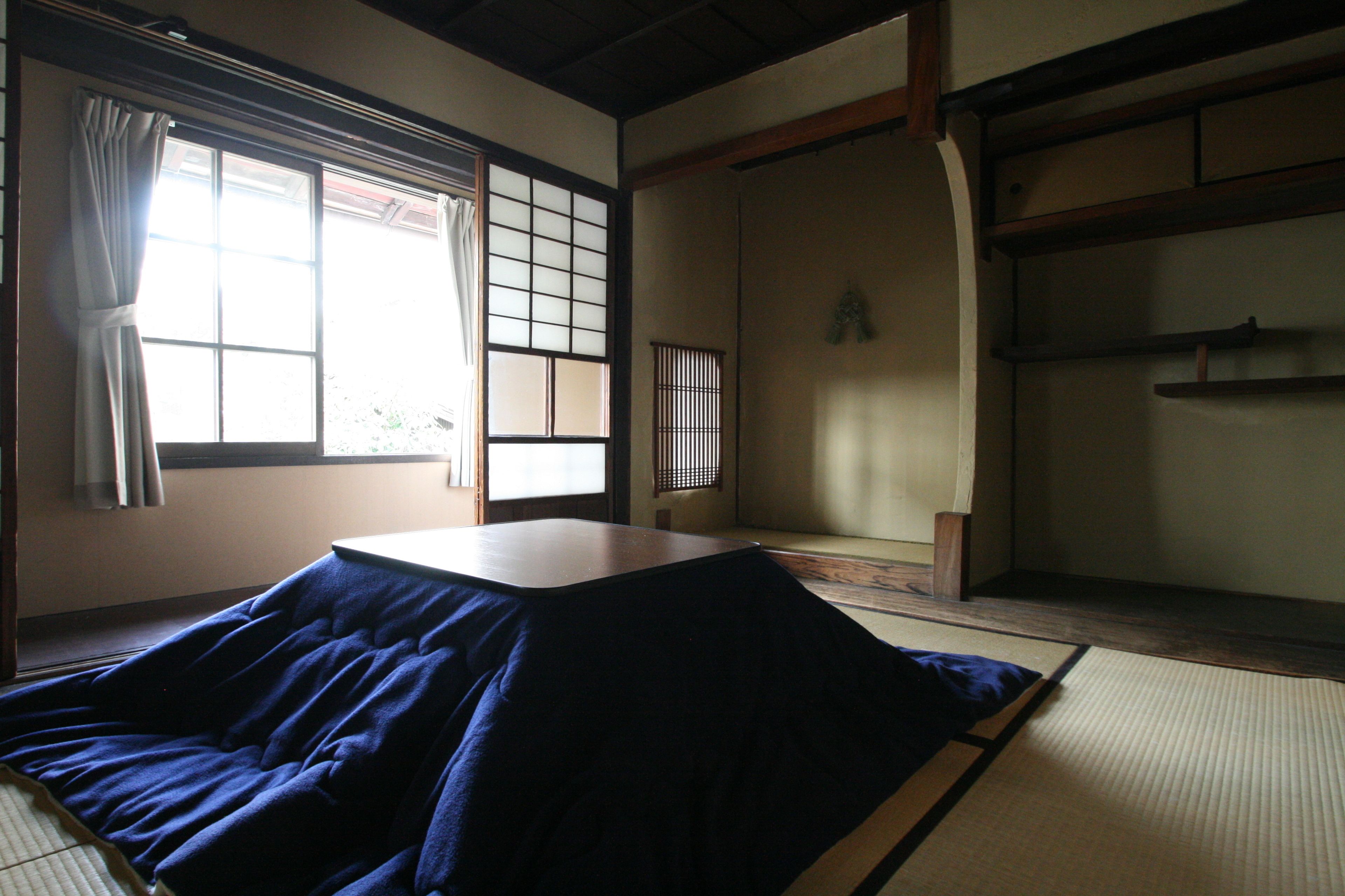 A traditional Japanese room with tatami flooring, a low table, and sliding doors.