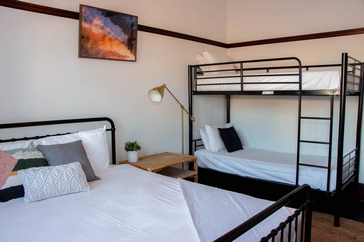 A bunk bed room with a single bed, a desk, and a lamp.