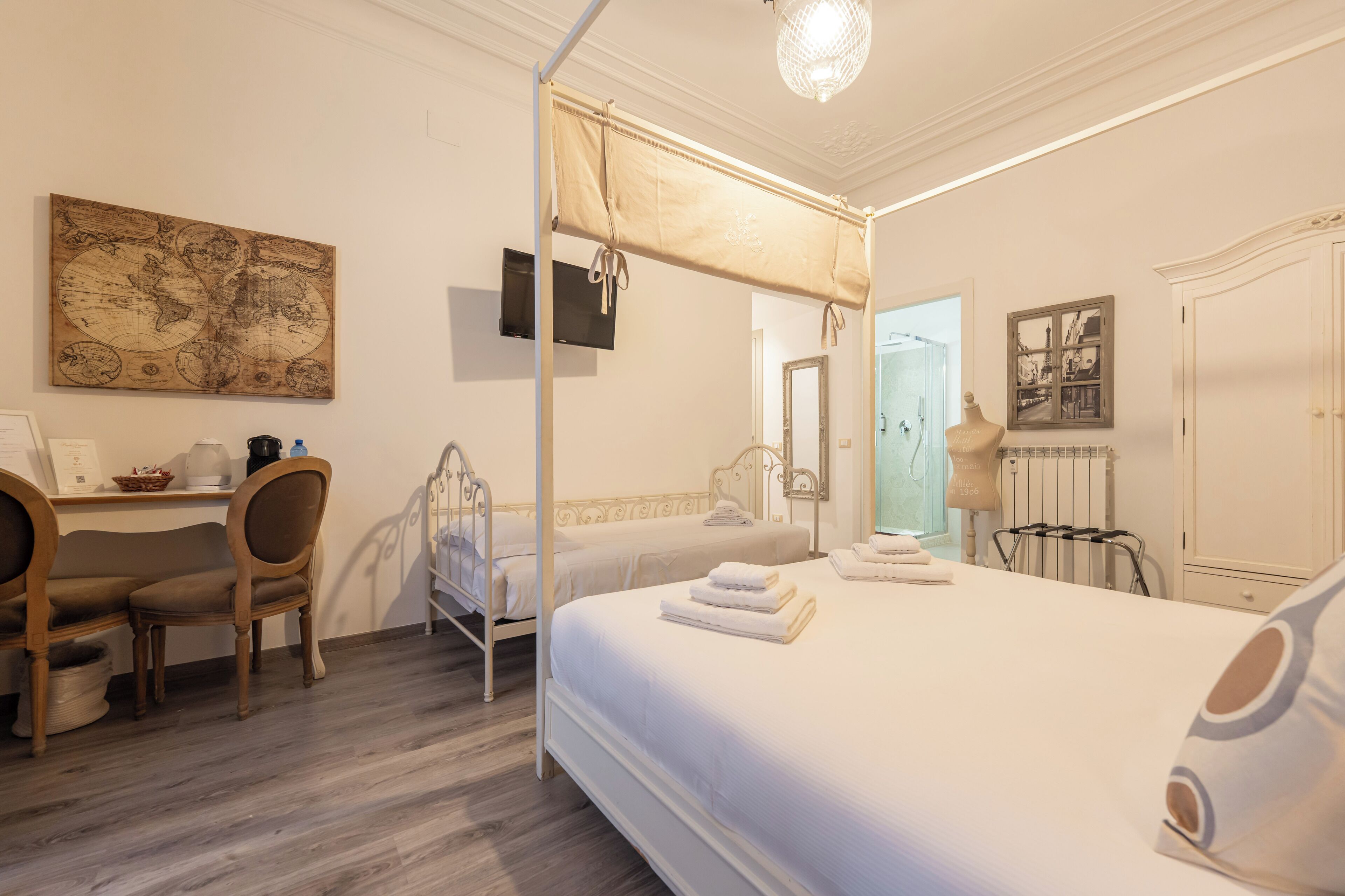A bedroom with a four-poster bed, a desk with a chair, and a map on the wall.