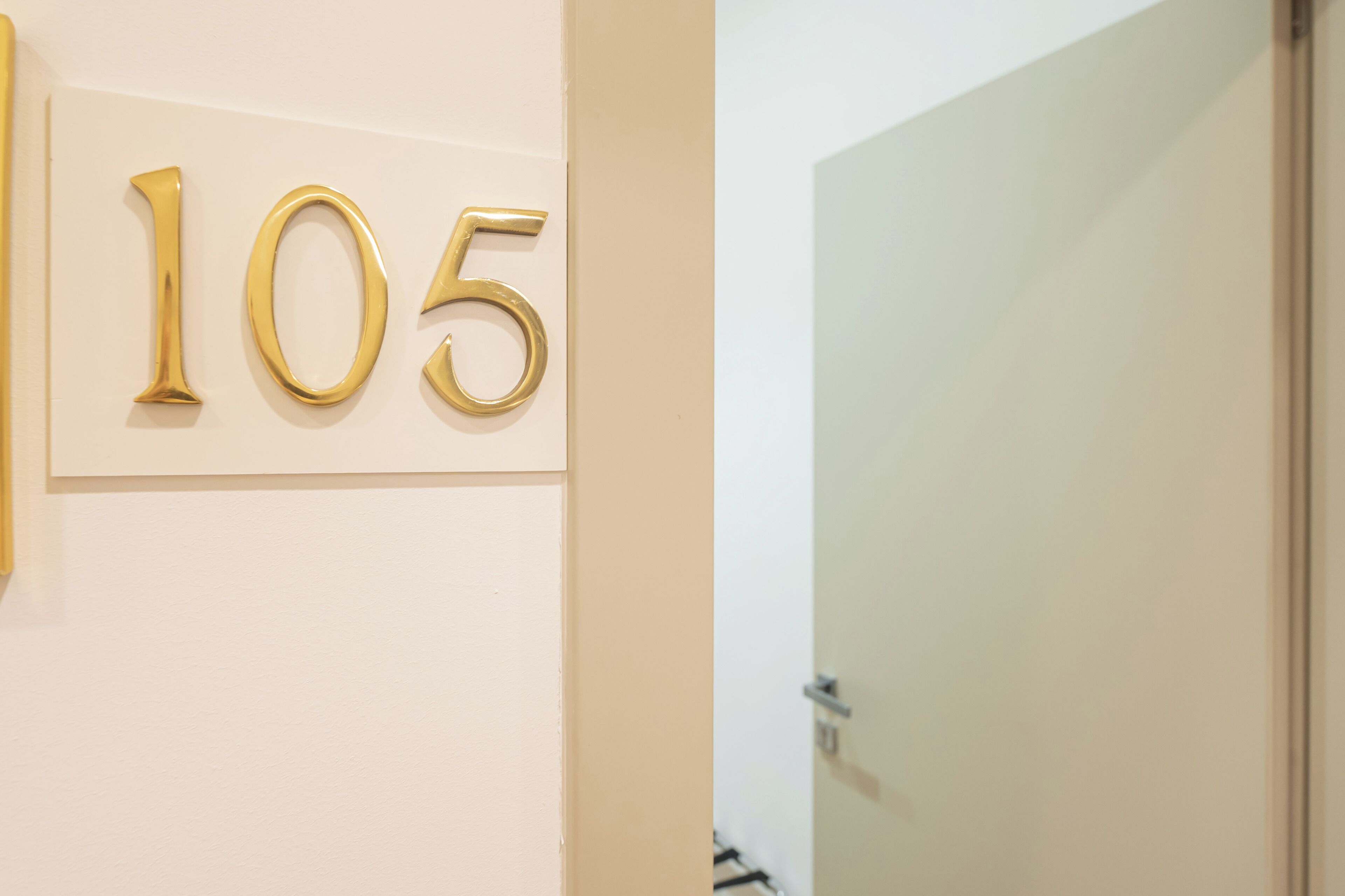 A gold number '105' on a white wall.