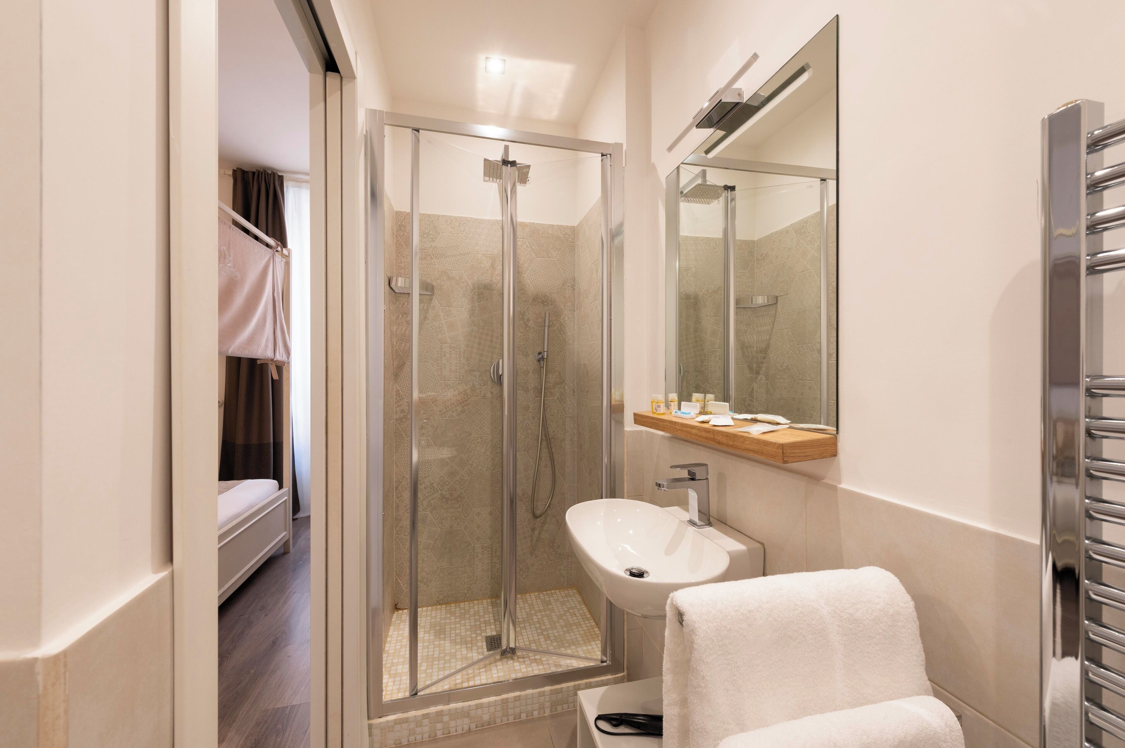A modern bathroom with a glass-enclosed shower, a white sink, and a mirror above it.