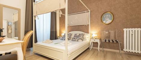 A four-poster bed with a canopy, a bedside table with a lamp, a round mirror, and a radiator.