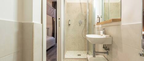 A modern bathroom with a glass-enclosed shower, a white sink, and a mirror above it.