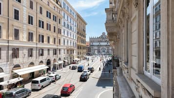 A street with historic buildings, a tram, and parked cars.