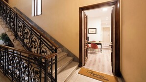 A hotel entrance with a wooden staircase, a reception desk, and a door marked "5". - Flaminia Rooms&Suites (Rome)