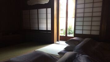 Een traditionele Japanse kamer met tatami vloerbedekking, een laag houten bed en shoji schermen.