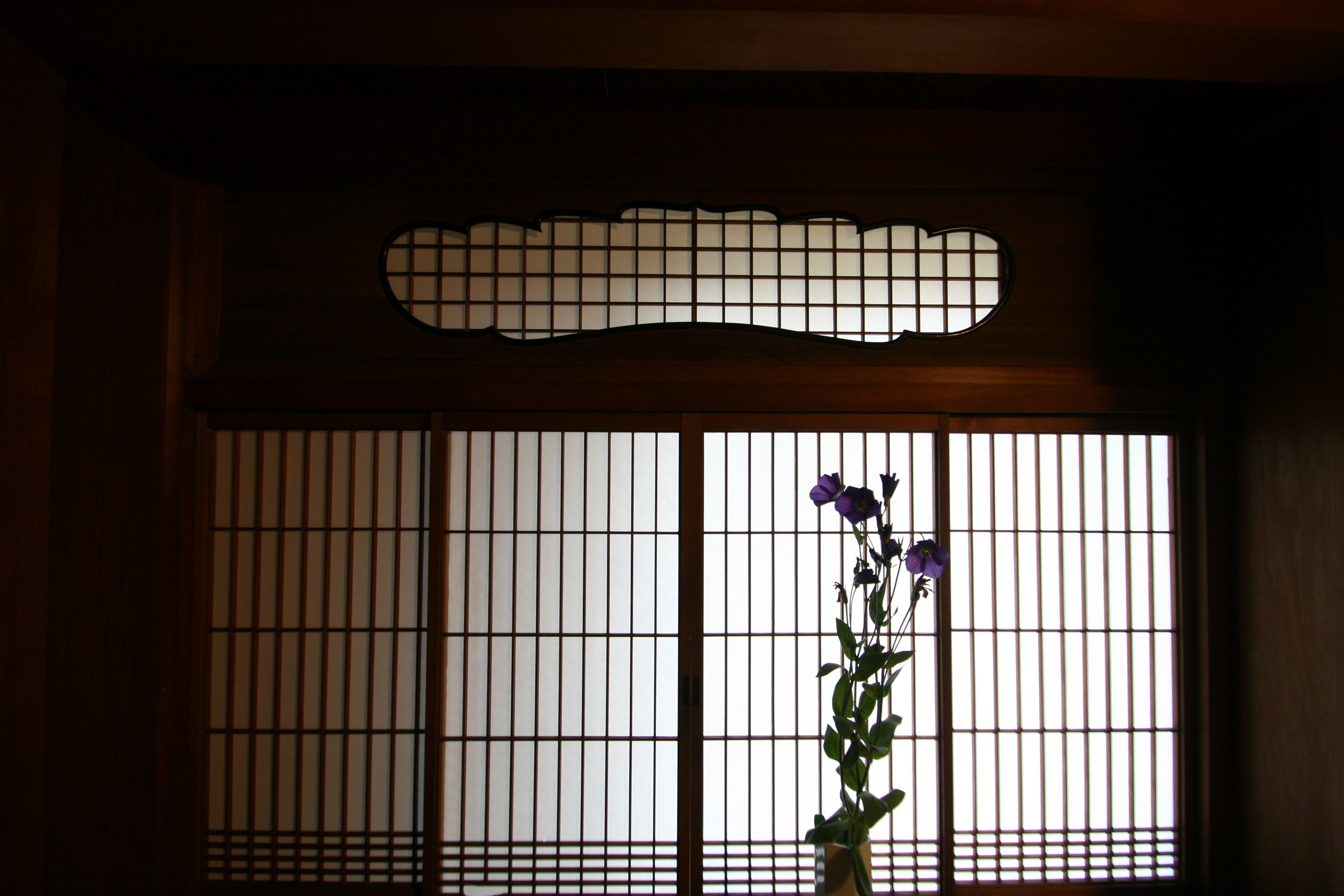 A traditional Japanese shoji screen with a floral arrangement in front.