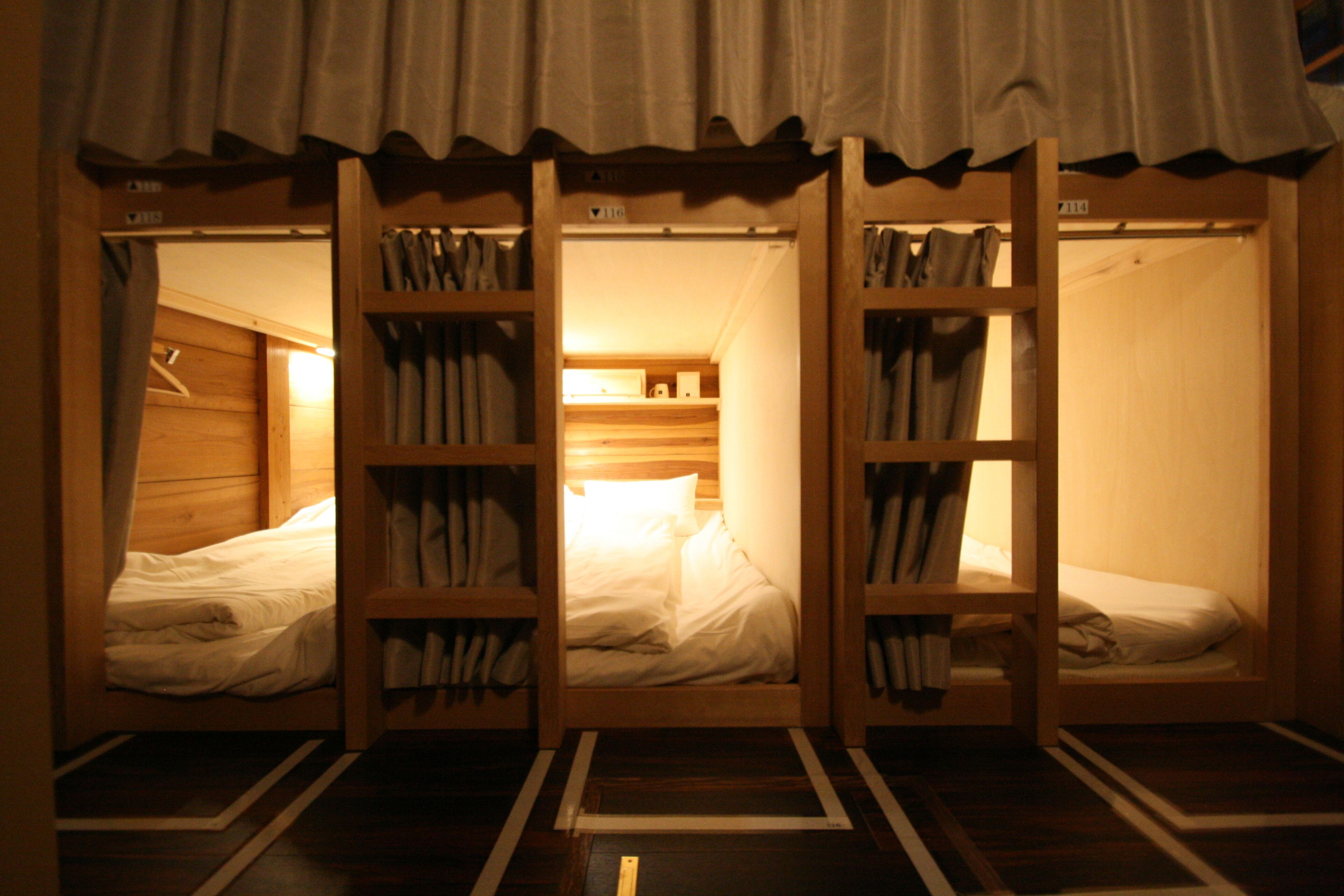 A room with three wooden bunk beds, each with a shelf above.