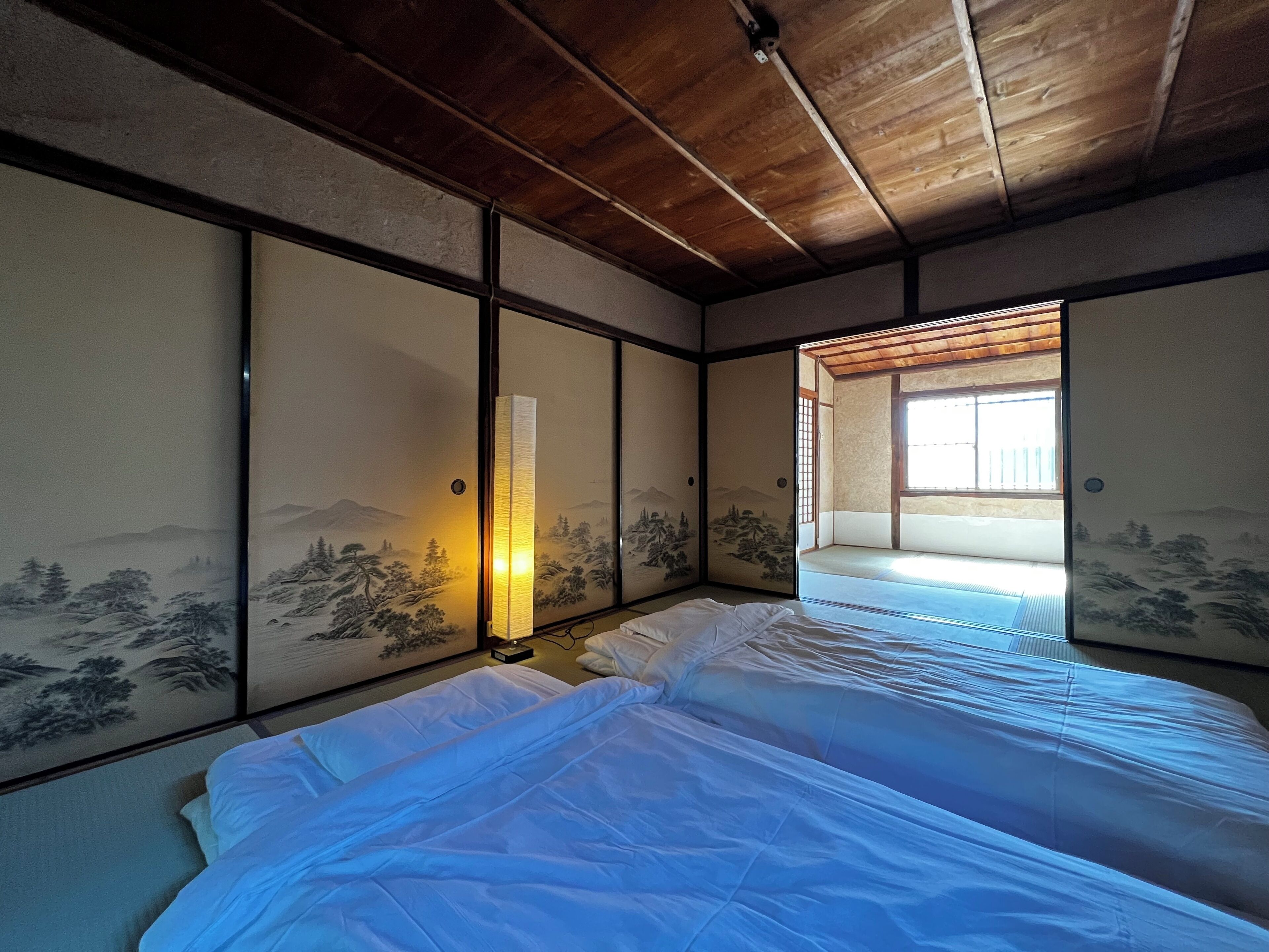 A traditional Japanese room with tatami flooring, shoji screens, and a futon bed.