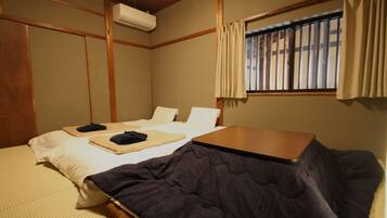A hotel room with two beds, a wooden table, and a window with curtains.