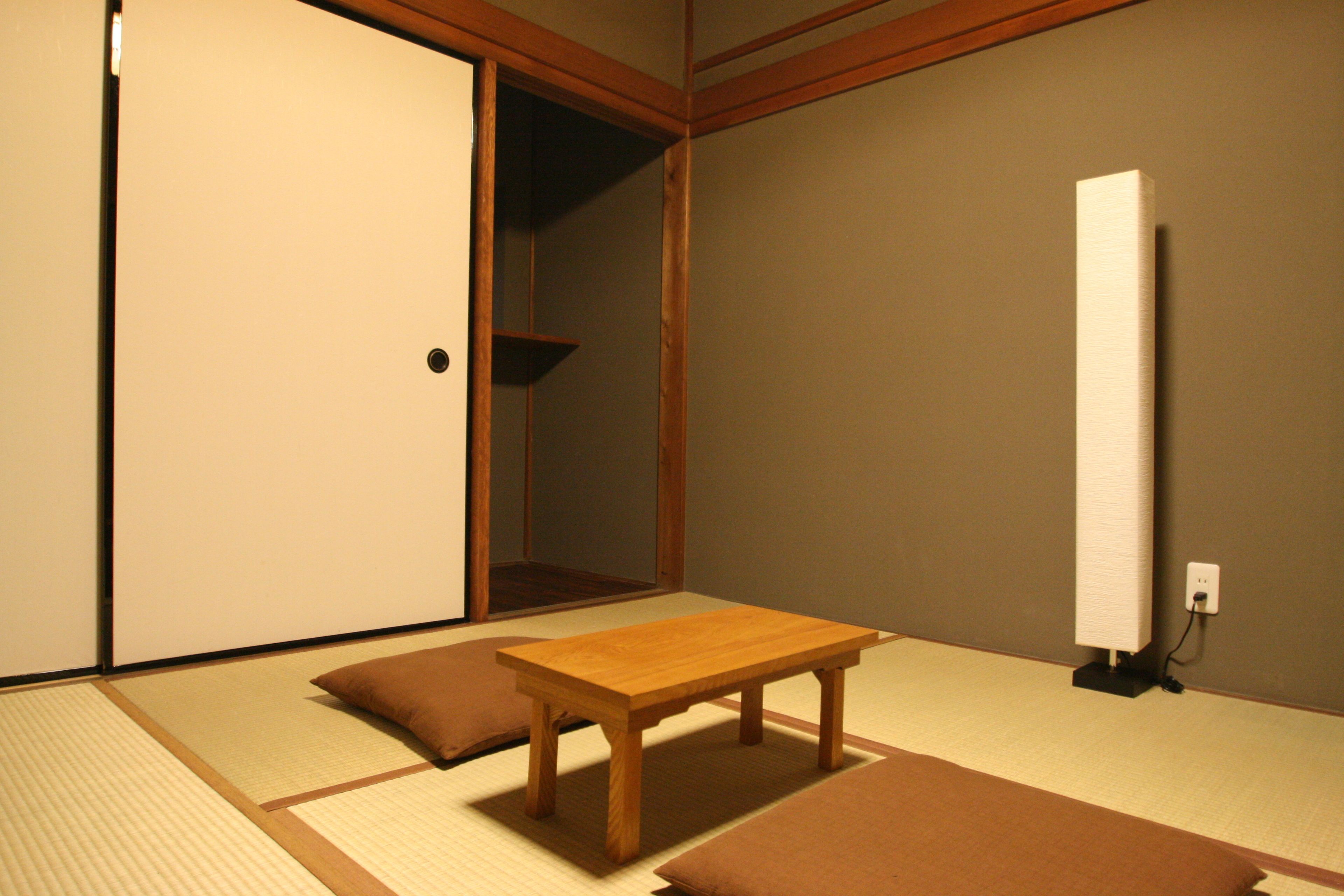 Um quarto japonês tradicional com tatames, uma mesa de madeira e almofadas.