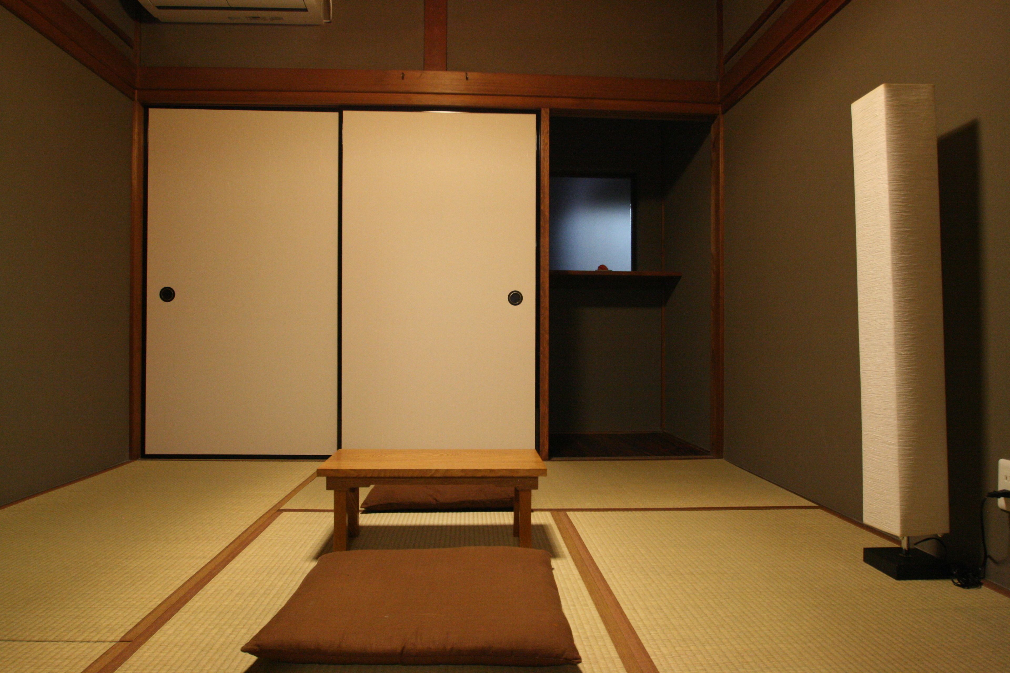 Une pièce de style japonais traditionnel, avec un sol recouvert de tatamis, une petite table en bois et une porte coulissante en papier de riz (shoji).