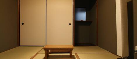 Une pièce de style japonais traditionnel, avec un sol recouvert de tatamis, une petite table en bois et une porte coulissante en papier de riz (shoji).