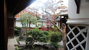 A traditional Japanese garden with a wooden fence, a stone pathway, and various plants and trees. - HARUYA Naramachi - Hostel (Nara)