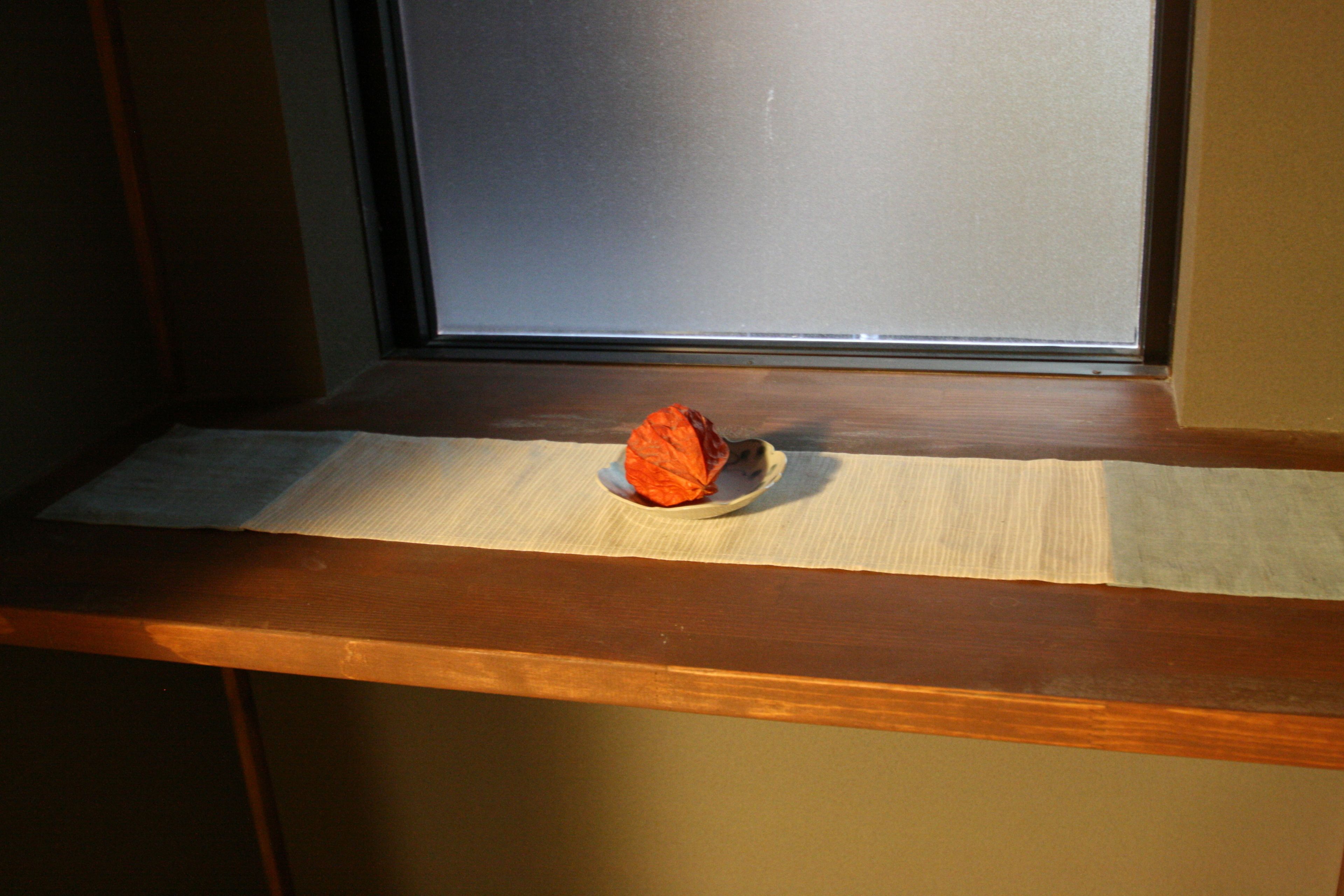 A window sill with a tissue and a red object on a plate.