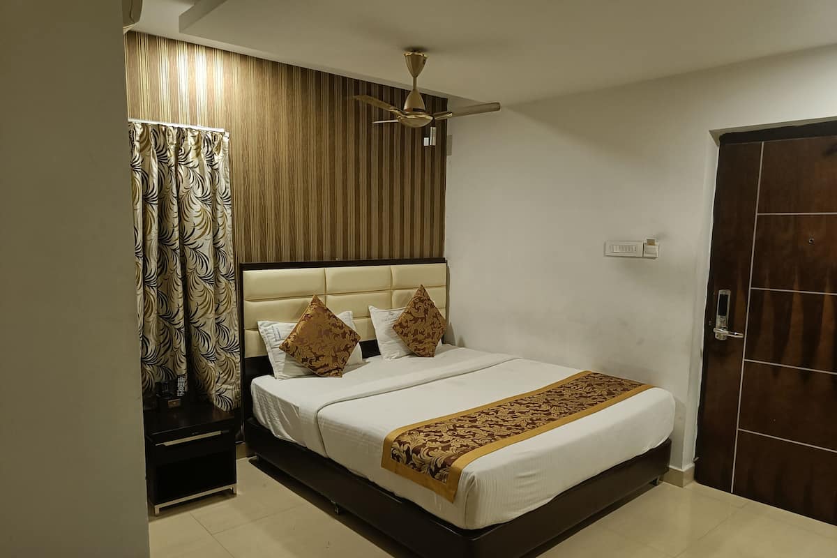 A neatly made bed with a headboard, a ceiling fan, and a door to the right.