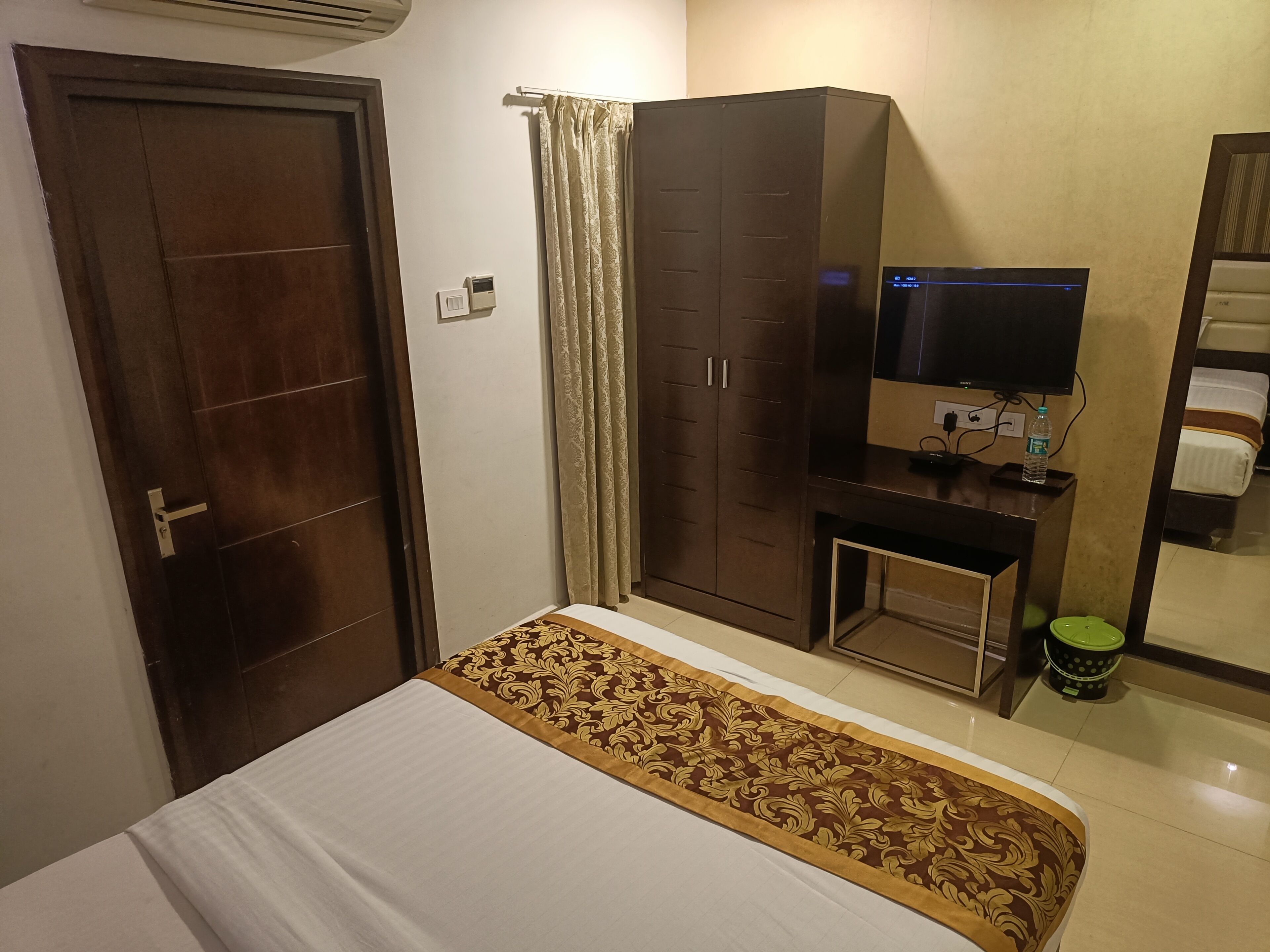 Une chambre d’hôtel avec un lit, une armoire, une télévision et une petite table.