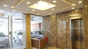 Un espace d’accueil avec un mur en marbre, un bureau d’information touristique et un ascenseur.
