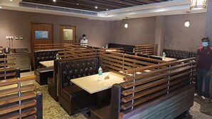 Un restaurant avec des banquettes, des tables en bois et un design moderne au niveau du plafond.