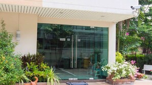 A modern building with a glass entrance, potted plants, and a security camera. - Jitthamas Residence (Bangkok)