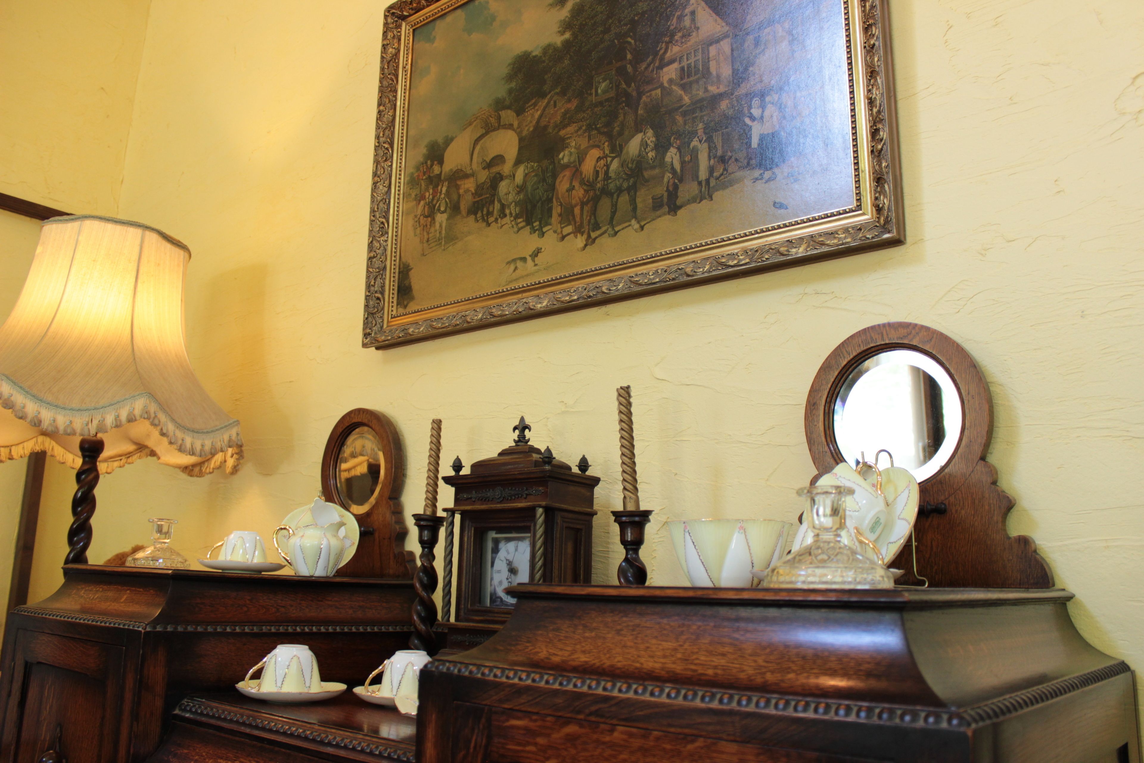 Un aparador de madera antiguo con espejo, un reloj y una lámpara.