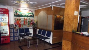 Una zona de recepción con un refrigerador de Coca-Cola, sillas azules, una mesa de centro de vidrio y un mural en la pared.
