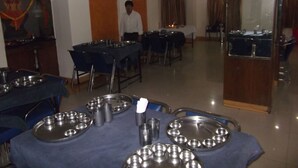 Un comedor con mesas dispuestas para una comida, incluyendo platos y tazas de metal.