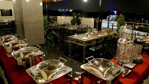Un restaurant doté d’une terrasse, protégée par un auvent rouge, et offrant un service de type buffet.