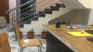 A kitchen with a wooden countertop, a chair, a potted plant, and a staircase. - Housefinch Residency (Bengaluru)
