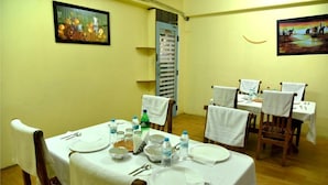 A dining area with a table set for four, chairs, and a door leading to another room. - Housefinch Residency (Bengaluru)