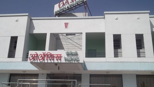 Un edificio con un letrero que dice "OASIS Organic & Natural Spring" y otro letrero con texto en un alfabeto diferente.