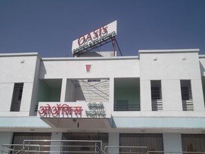 A building with a sign that reads "OASIS Organic & Natural Spring" and another sign with text in a different script.