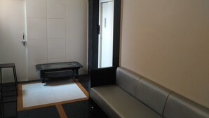 Quarto de hotel moderno com sofá, uma mesinha e porta com janela.