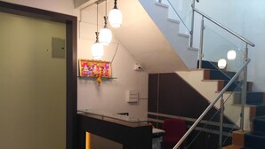 Interior moderno com escada, balcão de recepção e um objeto decorativo fixado na parede.
