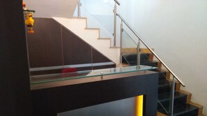 Uma escadaria moderna com guarda-corpos de vidro e acabamento em madeira escura.