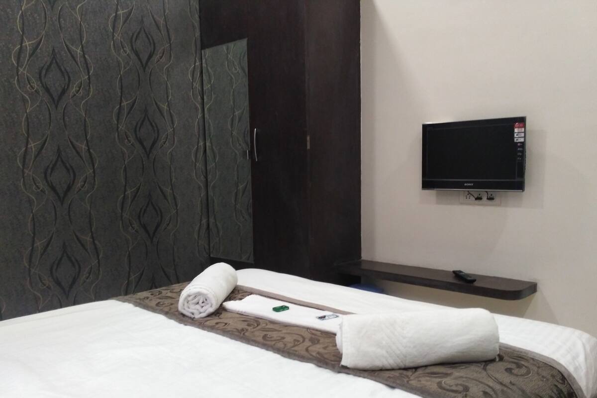 Habitación de hotel con cama, televisor montado en la pared y toalla sobre la cama.