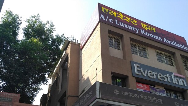 Um edifício com placas indicando 'Quartos de Luxo com Ar Condicionado Disponíveis' e 'Everest Inn'.