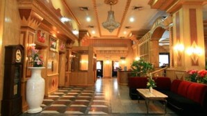 A hotel lobby with a checkered floor, a large white vase, a red sofa, and a chandelier. - 13 Coins Ngamwongwan Hotel (Nonthaburi)